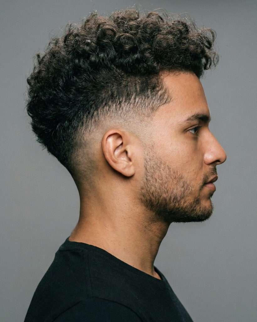 Homem de lado com corte de cabelo degrade medio e com cachos