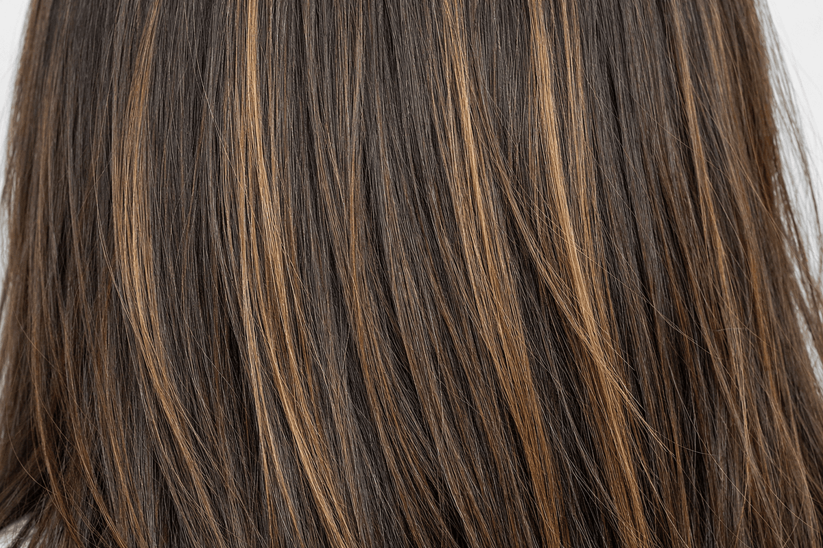 Detalhe de cabelo liso castanho com mechas mel finas